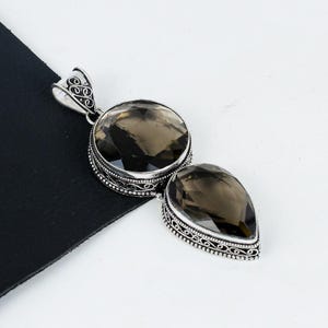 May include: A silver pendant featuring two smoky quartz stones. The stones are set in a filigree design.