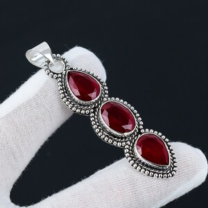 May include: Silver pendant featuring three teardrop-shaped red gemstones set in ornate silver settings.