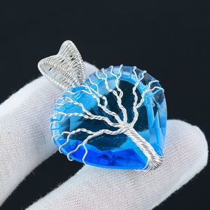 Peut inclure: Un pendentif en fil d'argent avec un motif d'arbre de vie et une pierre en cristal bleu en forme de cœur.