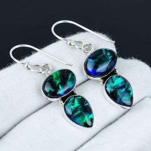 Könnte beinhalten: Ein Paar silberne Ohrhänger mit zwei tropfenförmigen grünen und blauen Opal-Steinen.