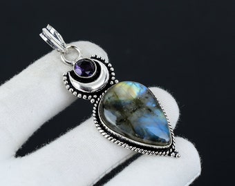 Puede incluir: Colgante de plata con una piedra de labradorita en forma de lágrima, una luna creciente y un acento de amatista. El colgante tiene un diseño de plata detallado.