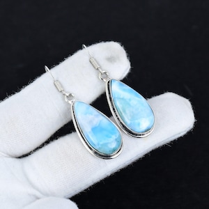 Op de afbeelding: Een paar zilveren oorhangers met traanvormige blauwe en witte edelsteen druppels.