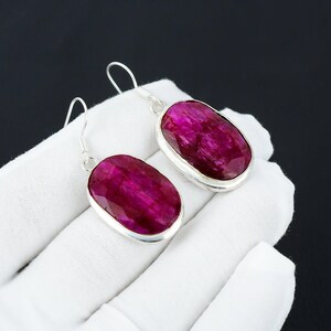 Puede incluir: Un par de pendientes de plata con piedras preciosas de rubí de forma ovalada. Los pendientes tienen un diseño sencillo y son perfectos para el uso diario.