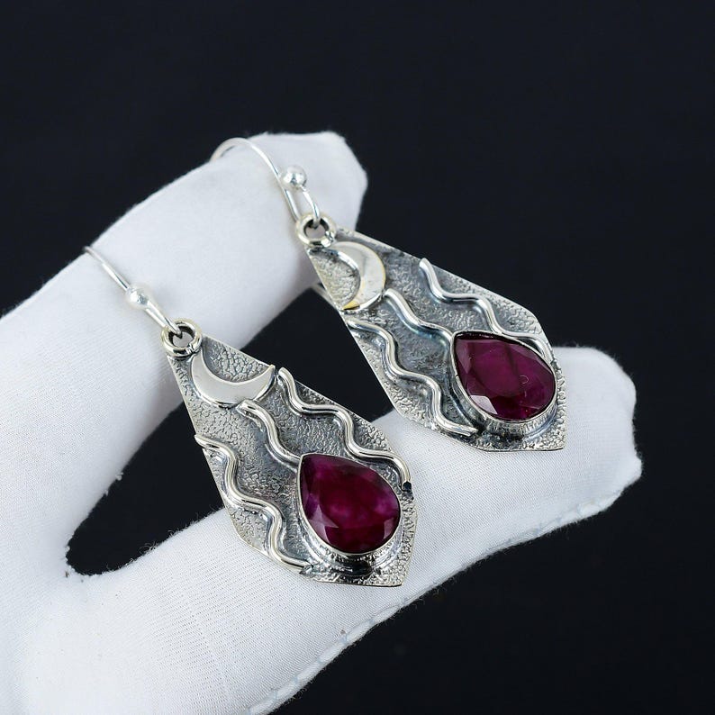 Peut inclure: Une paire de boucles d'oreilles pendantes en argent avec un motif de croissant de lune et une pierre pr&eacute;cieuse en forme de larme de rubis.