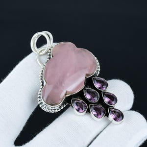 May include: A silver pendant featuring a pink cloud-shaped gemstone with a silver bail and a cluster of purple gemstones hanging below.