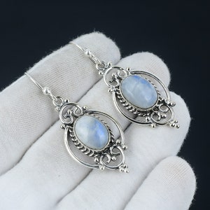 May include: Silver dangle earrings with a moonstone oval cabochon set in a filigree design.