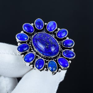 May include: A silver ring with a large oval lapis lazuli stone surrounded by smaller lapis lazuli stones.