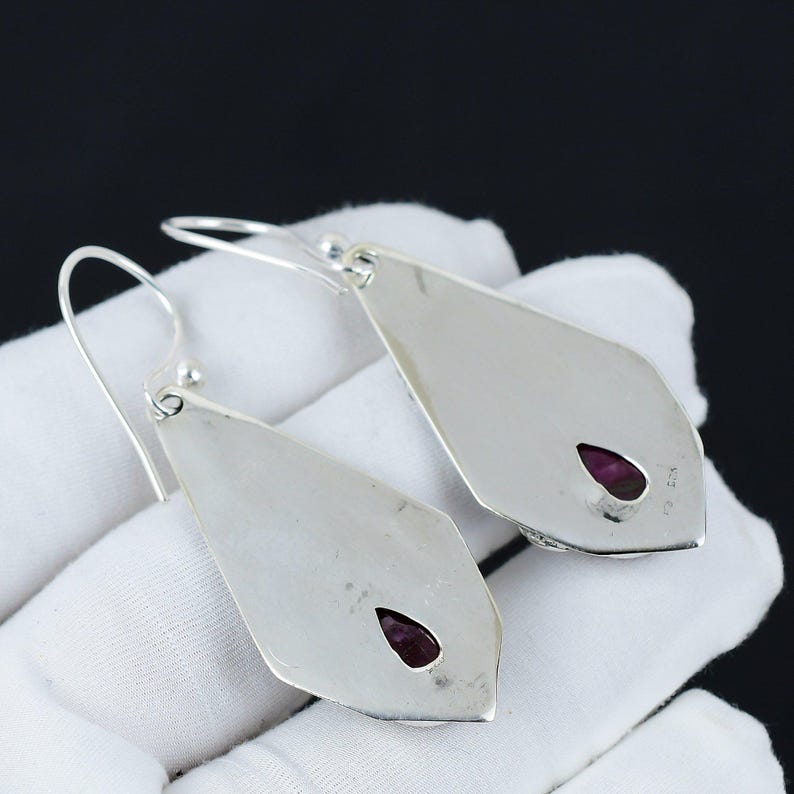 Peut inclure: Une paire de boucles d'oreilles pendantes en argent avec une pierre pr&eacute;cieuse violette en forme de larme sertie dans chaque boucle d'oreille.