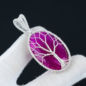 May include: A silver wire wrapped pendant featuring a pink agate stone with a tree of life design.