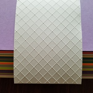 May include: White embossed paper with a diamond pattern. The paper has a subtle texture and a slightly off-white color.