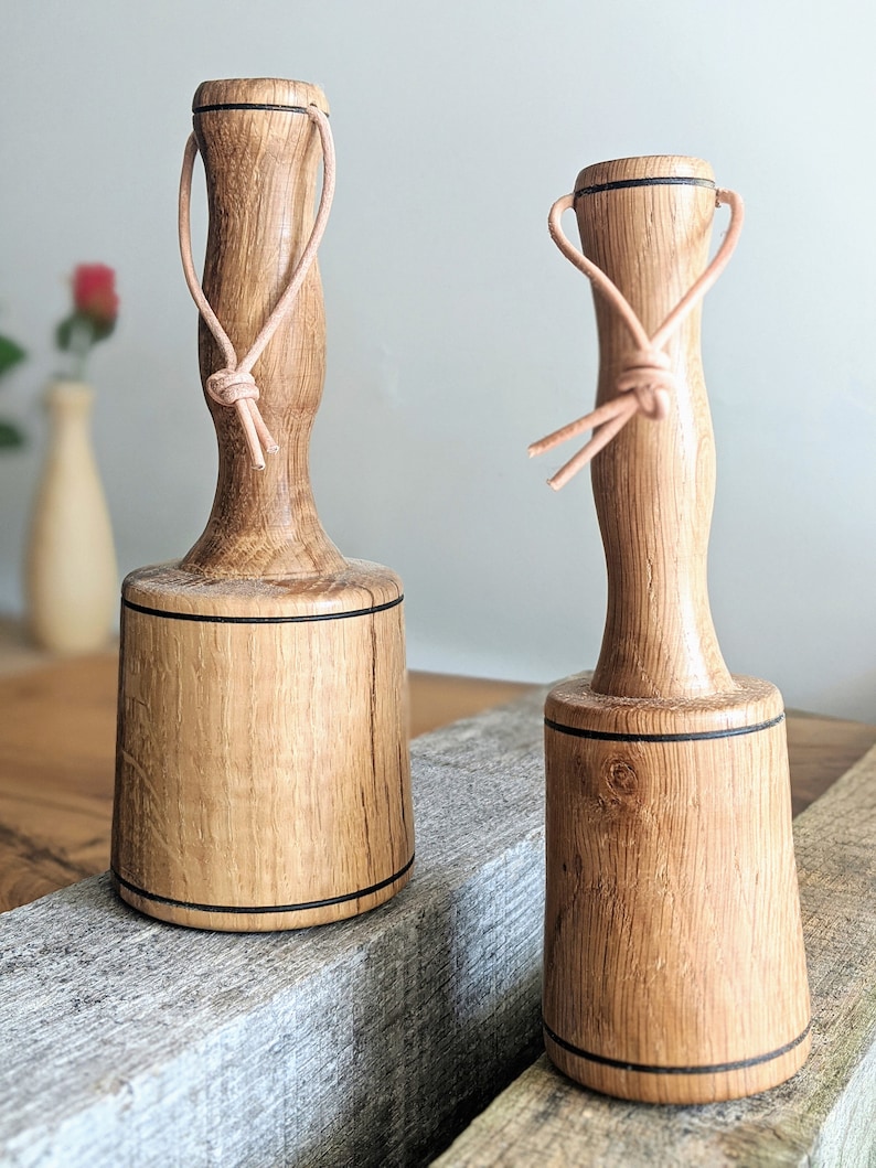 May include: Two wooden mallets with leather loops. The mallets are brown with black accents and have a rounded head.