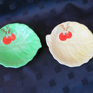 Könnte beinhalten: Zwei Keramik-Schalen in Blattform mit erhabenen Details, eine grün und eine gelb, jede mit zwei roten Tomatenmotiven.