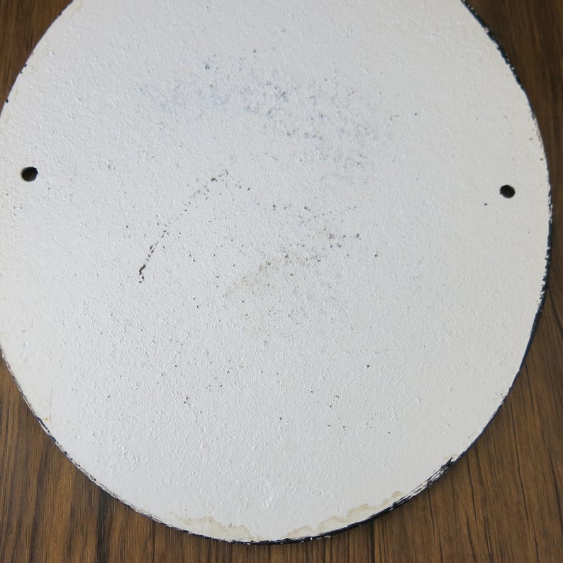 May include: White round metal sign with two small holes near the edge. The sign has a slightly textured surface and appears to be blank.