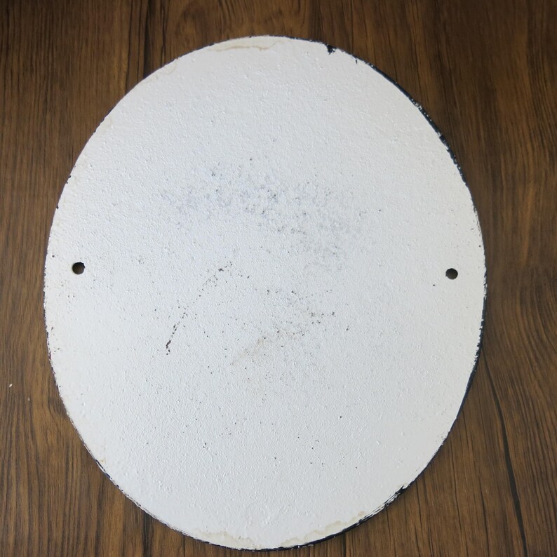 May include: A white round metal sign with a black border. The sign has two small holes on the top and bottom for hanging. The sign is blank.