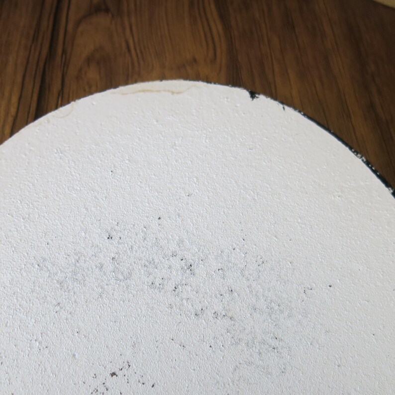 May include: White round ceramic plate with a black rim. The plate has a textured surface and some black specks.