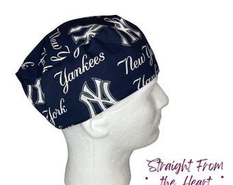 May include: A navy blue surgical cap featuring the New York Yankees logo and team name in white script. The cap is designed to cover the head and is made of a patterned fabric.