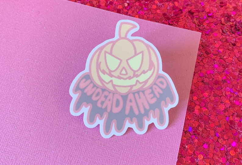 May include: A pink and black sticker with a cartoon pumpkin and the text "UNDEAD AHEAD" dripping from the bottom.