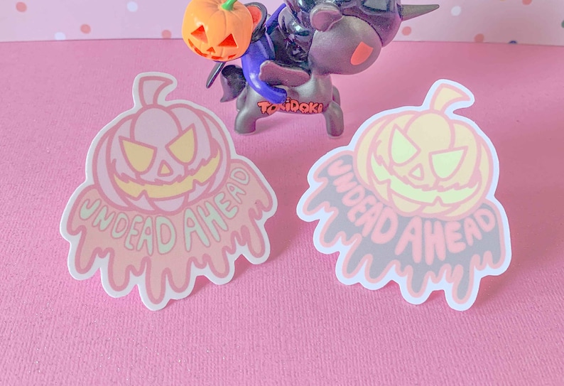 May include: Two Halloween-themed stickers with a dripping pumpkin design. The stickers are pink and gray with the text "Undead Ahead" in a dripping font.
