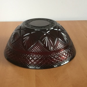 May include: A large, dark red glass bowl with a diamond pattern. The bowl is made of heavy glass and has a deep, round shape.