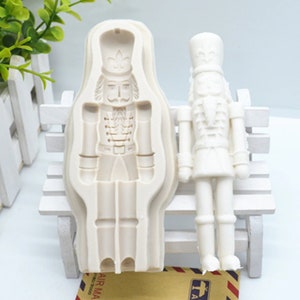 May include: White silicone mould for making a nutcracker figurine. The mould is shown next to a finished nutcracker figurine.