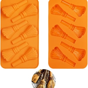 May include: Two orange silicone molds, each with multiple broom-shaped cavities. The molds are rectangular with a small hole at the top for hanging. A close-up shows miniature brooms.