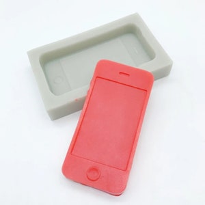 May include: A red silicone mold shaped like a smartphone. The mold is used to create a replica of a smartphone.