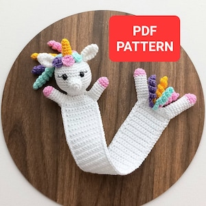 May include: Crochet unicorn bookmark pattern in PDF format. The bookmark is white with a colorful unicorn head and tail.