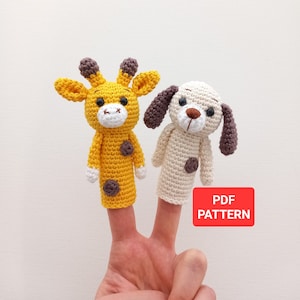Könnte beinhalten: Zwei Fingerpuppen, eine gelbe Giraffe und ein weißer Hund, werden an den Fingern einer Person getragen. Die Puppen sind gehäkelt und haben braune Augen und Nasen. Der Text "PDF PATTERN" befindet sich auf einem roten Rechteck.