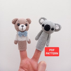 May include: Crochet finger puppets of a brown bear wearing a blue bow tie and a gray koala. The puppets are on a person's fingers. The text "PDF PATTERN" is on a red rectangle.