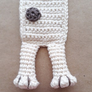 Puede incluir: Marcap&aacute;ginas de crochet blanco con detalles marrones. El marcap&aacute;ginas tiene forma de perro con dos patas y una nariz marr&oacute;n.