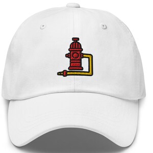 May include: White baseball cap featuring an embroidered design of a red fire hydrant with yellow hose and nozzle. The cap has a curved brim and a classic six-panel construction. A casual accessory for everyday wear.
