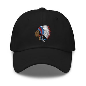 Puede incluir: Gorra de béisbol negra con una imagen bordada de un jefe nativo americano con un tocado con plumas rojas, blancas y azules.