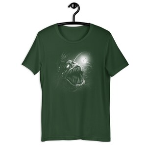 K&ouml;nnte beinhalten: Ein dunkelgr&uuml;nes T-Shirt mit einem wei&szlig;en Grafikdruck eines Tiefsee-Anglerfisches mit einem biolumineszierenden K&ouml;der.