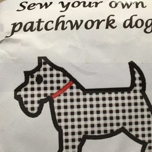 May include: A white package with the black text Sew your own patchwork dog printed at the top. Below the text is a graphic illustration of a dog with a black and white chequered pattern and a solid red collar, outlined in thick black lines.