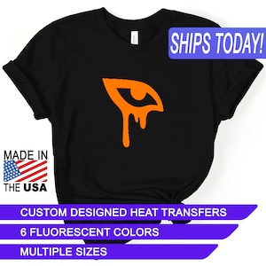 May include: Black t-shirt with an orange dripping eye graphic. The text "SHIPS TODAY!" is in a blue box in the upper right corner. The text "MADE IN THE USA" is in a red, white, and blue box in the lower left corner. The text "CUSTOM DESIGNED HEAT TRANSFERS", "6 FLUORESCENT COLORS", and "MULTIPLE SIZES" are in purple boxes at the bottom of the image.