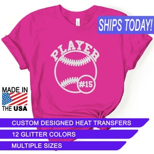 May include: Pink t-shirt with a white glitter design that says "PLAYER" with a baseball and the number "#15". The shirt is made in the USA and is available in multiple sizes and 12 glitter colors.