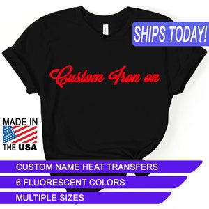 May include: Black t-shirt with the text "Custom Iron on" in red cursive lettering. The shirt is made in the USA and is available in multiple sizes and 6 fluorescent colors.