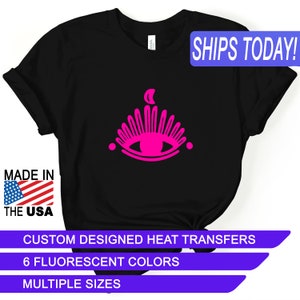 May include: Black t-shirt with a pink eye and crescent moon design. The text "SHIPS TODAY!" is in a blue box in the upper right corner. The text "MADE IN THE USA" is in a red, white, and blue box in the lower left corner. The text "CUSTOM DESIGNED HEAT TRANSFERS", "6 FLUORESCENT COLORS", and "MULTIPLE SIZES" are in blue boxes at the bottom of the image.