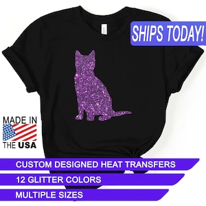 May include: Black t-shirt featuring a purple glitter cat silhouette. The shirt includes the text "MADE IN THE USA" and "SHIPS TODAY!". Additional text indicates custom heat transfers with 12 glitter colors and multiple sizes.