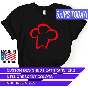 May include: Black t-shirt with a red chef hat graphic. The text "SHIPS TODAY!" is in a blue box in the upper right corner. The text "MADE IN THE USA" is in a red, white, and blue box in the lower left corner. The text "CUSTOM DESIGNED HEAT TRANSFERS", "6 FLUORESCENT COLORS", and "MULTIPLE SIZES" are in a purple box at the bottom of the image.