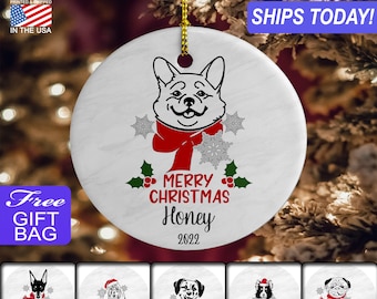 May include: White ceramic Christmas ornament with a black and white illustration of a dog wearing a red scarf and snowflakes. The ornament says "Merry Christmas Honey 2022".