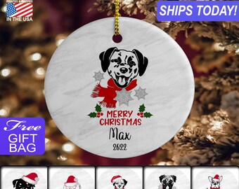 May include: White ceramic Christmas ornament with a black and white Dalmatian dog wearing a red scarf and snowflakes. The ornament says "Merry Christmas Max 2022".