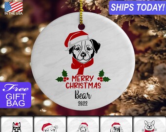 May include: White ceramic Christmas ornament with a black and white dog wearing a red Santa hat and a red scarf. The ornament says "Merry Christmas Bear 2022".