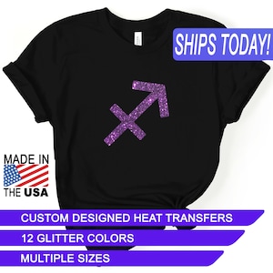 May include: Black t-shirt with a purple glitter Sagittarius zodiac sign. The text "SHIPS TODAY!" is in a blue box at the top of the image. The text "MADE IN THE USA" is in a red, white, and blue box at the bottom left of the image. The text "CUSTOM DESIGNED HEAT TRANSFERS" is in a purple box at the bottom of the image. The text "12 GLITTER COLORS" is in a purple box below the previous text. The text "MULTIPLE SIZES" is in a purple box below the previous text.