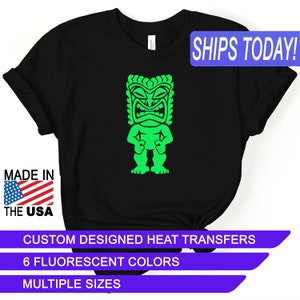 May include: Black t-shirt featuring a neon green tiki design. The shirt has the text "MADE IN THE USA" and "SHIPS TODAY!" The image also includes text that reads "CUSTOM DESIGNED HEAT TRANSFERS", "6 FLUORESCENT COLORS", and "MULTIPLE SIZES".