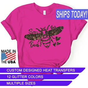 May include: Pink t-shirt with a black glitter design of a bee with the text "Save the Bees" and hearts. The shirt says "Ships Today!" and "Custom Designed Heat Transfers". It also says "12 Glitter Colors" and "Multiple Sizes".