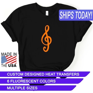 May include: Black t-shirt with an orange treble clef graphic. The text "SHIPS TODAY!" is in a blue box at the top of the image. The text "MADE IN THE USA" is in a red, white, and blue box at the bottom left of the image. The text "CUSTOM DESIGNED HEAT TRANSFERS", "6 FLUORESCENT COLORS", and "MULTIPLE SIZES" are in purple boxes at the bottom of the image.