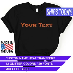 May include: Black t-shirt with the text "YOUR TEXT" in orange glitter. The shirt is made in the USA and has custom name heat transfers, 12 glitter colors, 20 fonts, and multiple sizes.