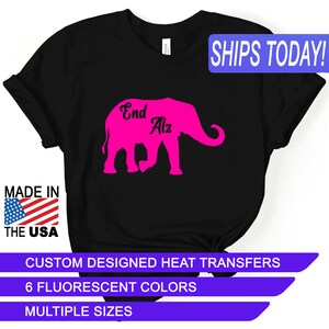 May include: Black t-shirt with a pink elephant silhouette and the text "End Alz" on the front. The shirt is made in the USA and is available in multiple sizes.