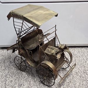 Peut inclure: Modèle de voiture ancienne en laiton avec auvent. Le véhicule antique présente des roues à rayons, un compartiment moteur détaillé et un siège conducteur. Le laiton a une finition ternie, lui donnant un aspect classique et vieilli. Une pièce décorative.